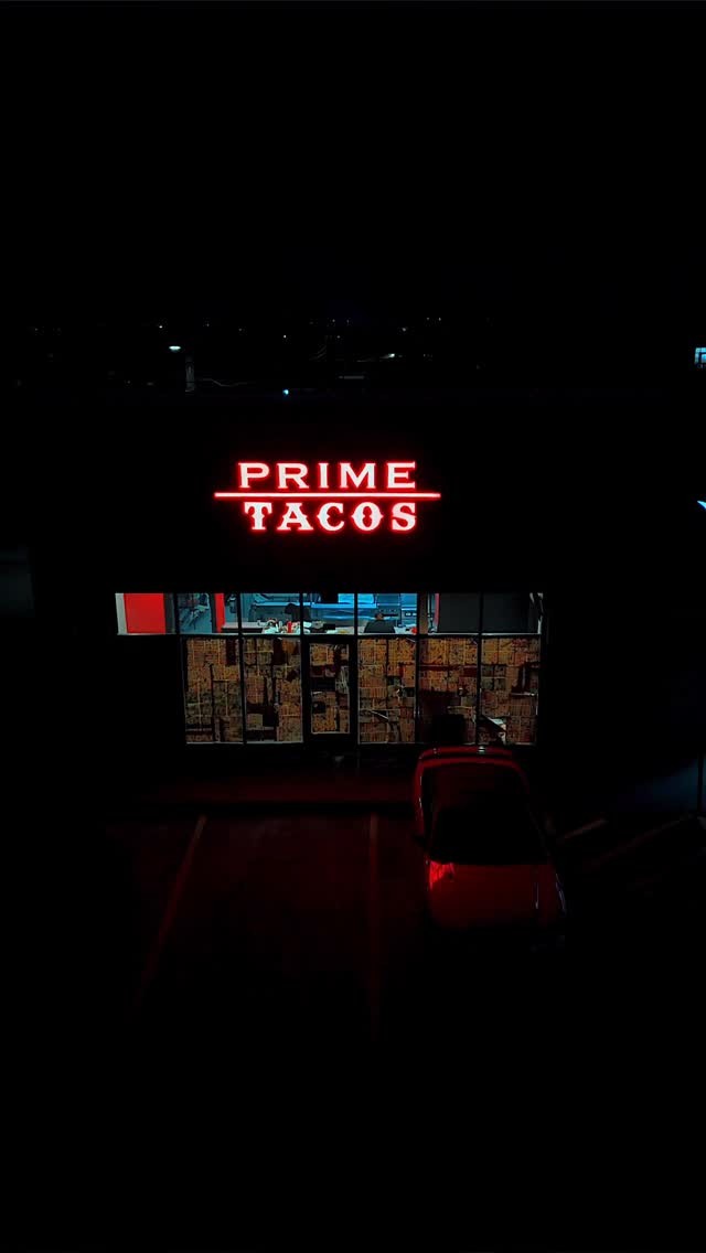 The Prime Tacos storefront on Harlem Avenue at night, red neon sign lit above the windows
