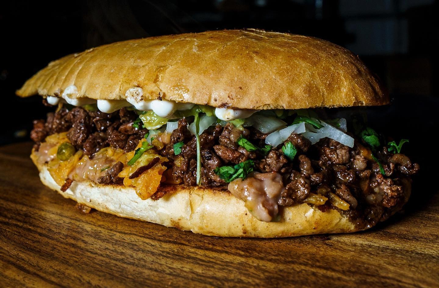 An arrachera torta on a wooden board, stuffed with grilled steak, onion and cilantro