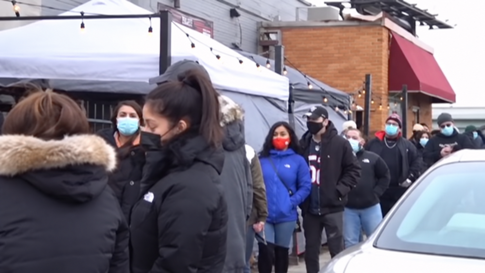 Customers in winter coats waiting shoulder to shoulder down the sidewalk outside the pop-up